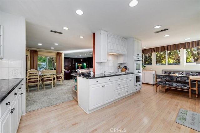 kitchen featuring white cabinetry, a healthy amount of sunlight, light hardwood / wood-style floors, and tasteful backsplash