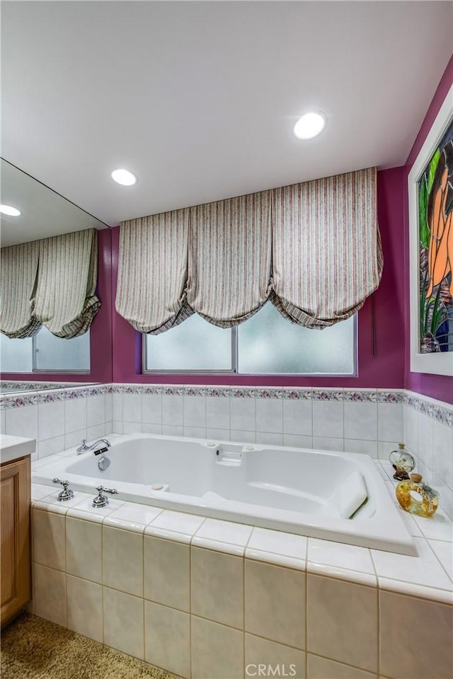 bathroom featuring vanity and tiled bath