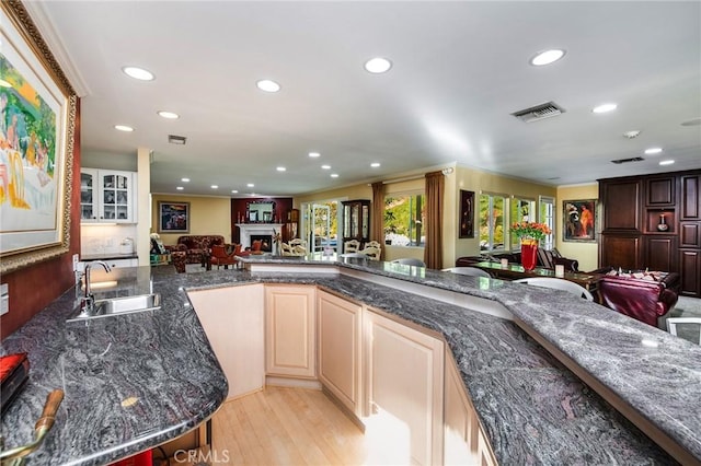 kitchen with sink, light hardwood / wood-style floors, and dark stone counters