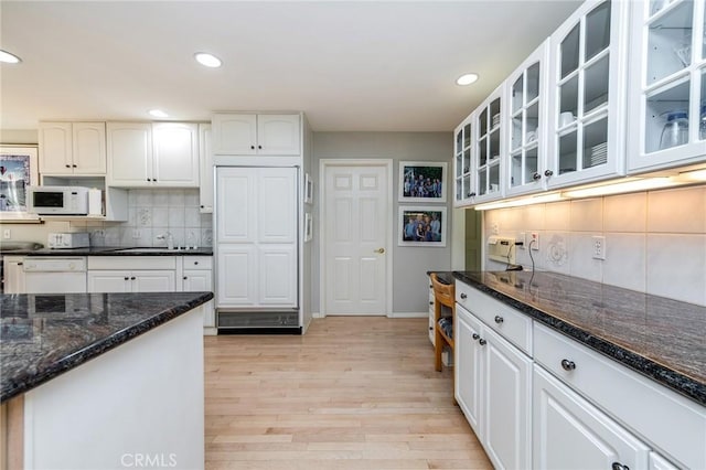 kitchen featuring sink, white cabinetry, white appliances, dark stone counters, and light hardwood / wood-style floors