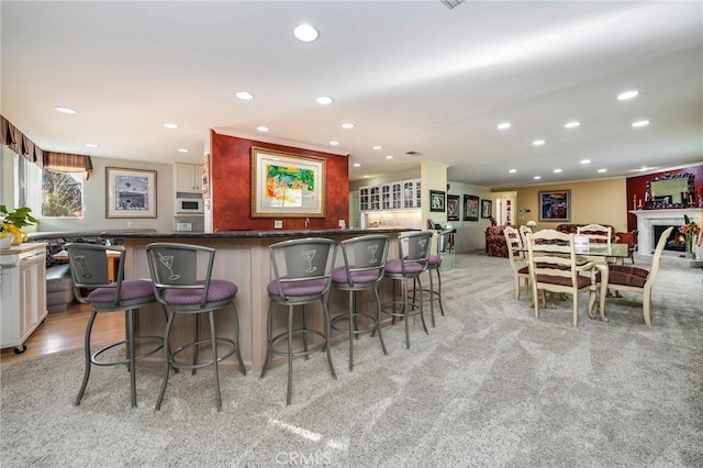 kitchen with stainless steel oven, a breakfast bar area, and light hardwood / wood-style floors