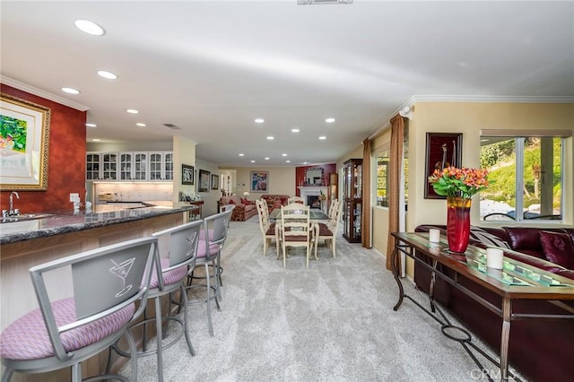 kitchen with crown molding, light colored carpet, and sink