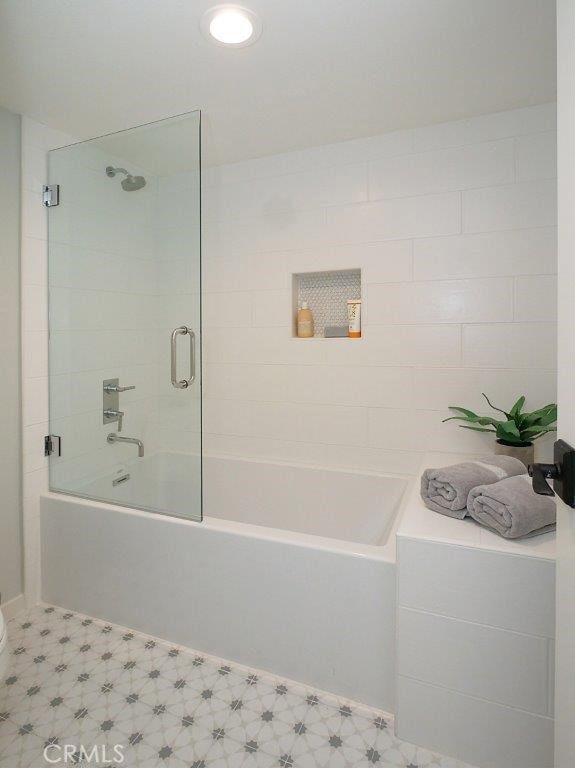 full bath with tile patterned floors and combined bath / shower with glass door