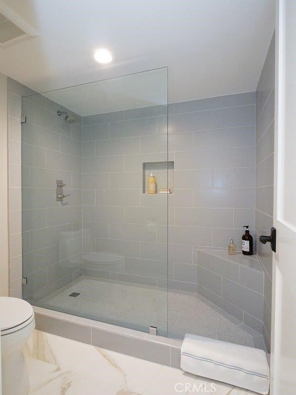 bathroom featuring tiled shower and toilet