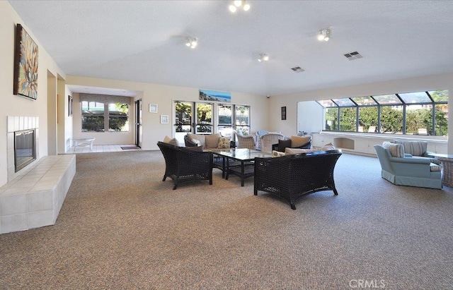 carpeted living room featuring plenty of natural light, a tile fireplace, and vaulted ceiling