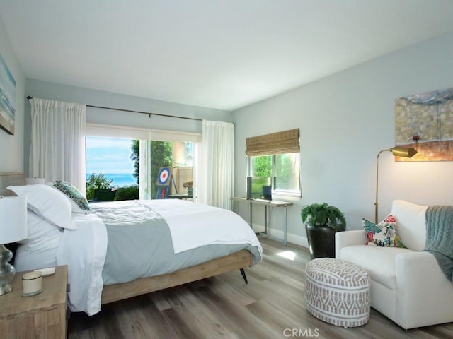 bedroom with baseboards, wood finished floors, and access to outside