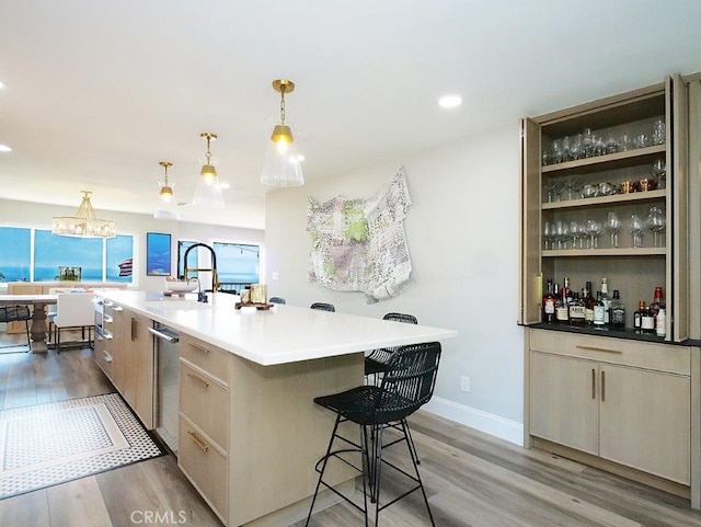 kitchen with hanging light fixtures, light hardwood / wood-style flooring, sink, and a large island with sink