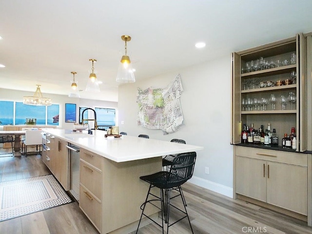 kitchen featuring a sink, a kitchen island with sink, a breakfast bar, and light wood-style flooring