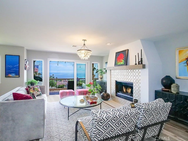 living room featuring wood-type flooring, a chandelier, and a tile fireplace