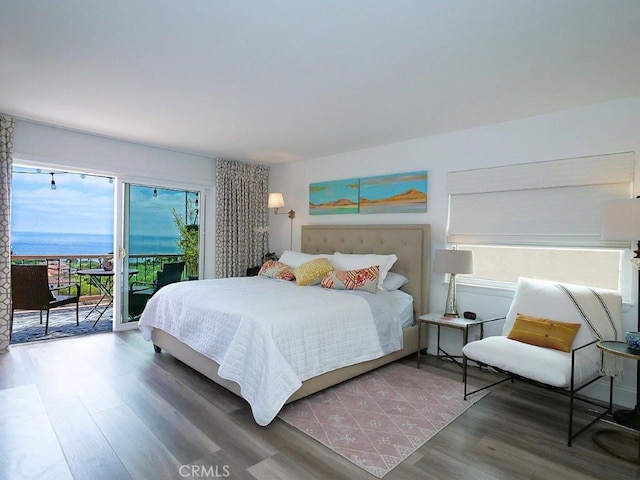 bedroom with a water view, dark hardwood / wood-style floors, and access to outside