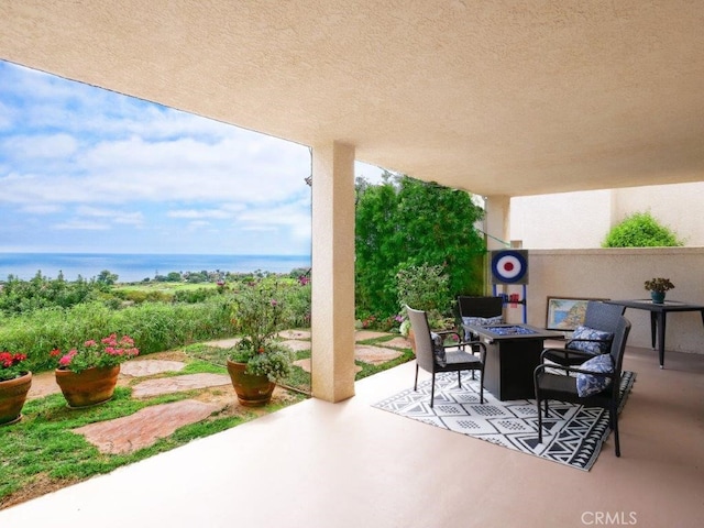 view of patio with a fire pit and a water view