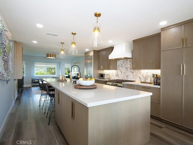 kitchen featuring backsplash, wood finished floors, light countertops, range, and custom exhaust hood