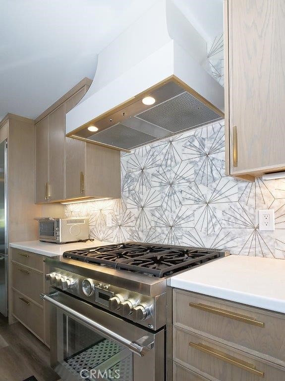 kitchen featuring high end stainless steel range oven, custom exhaust hood, light countertops, and decorative backsplash