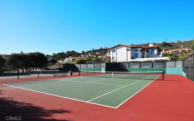 view of tennis court featuring community basketball court and fence