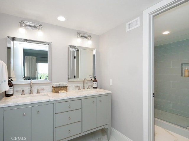 full bathroom with double vanity, visible vents, a tile shower, and a sink