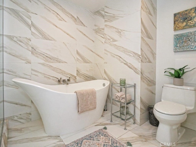 bathroom featuring tile walls, a soaking tub, marble finish floor, and toilet