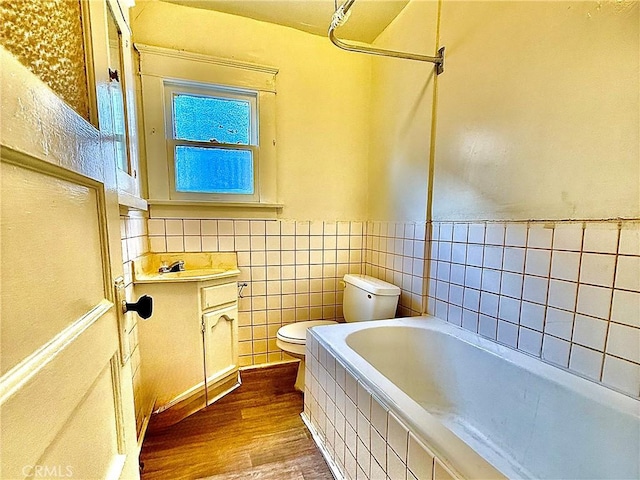 full bathroom with tile walls, hardwood / wood-style flooring, vanity, toilet, and bathing tub / shower combination