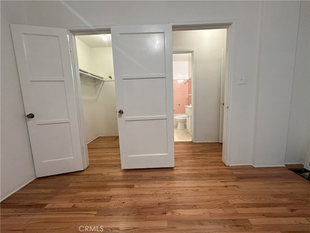 unfurnished bedroom with a spacious closet, light hardwood / wood-style flooring, a closet, and ensuite bathroom