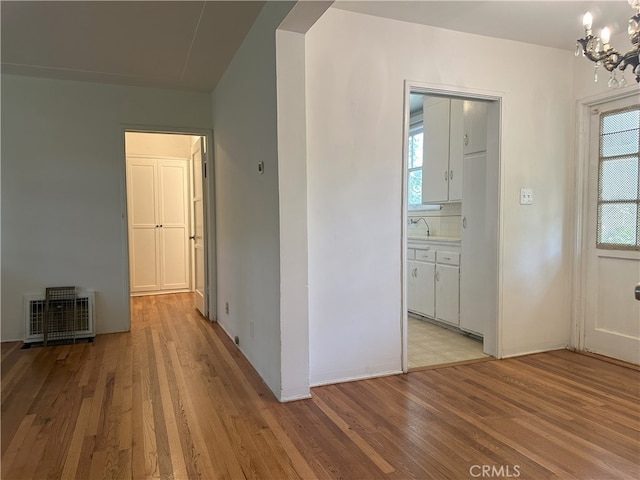 corridor with an inviting chandelier and light wood-type flooring