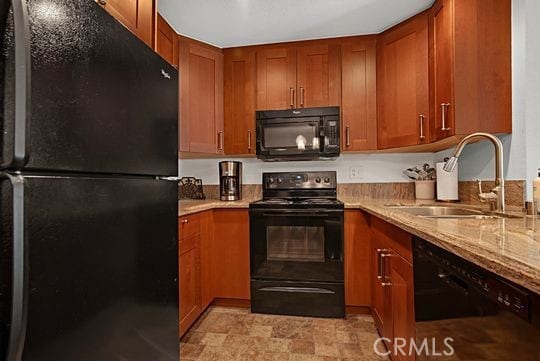 kitchen with sink, black appliances, and light stone countertops