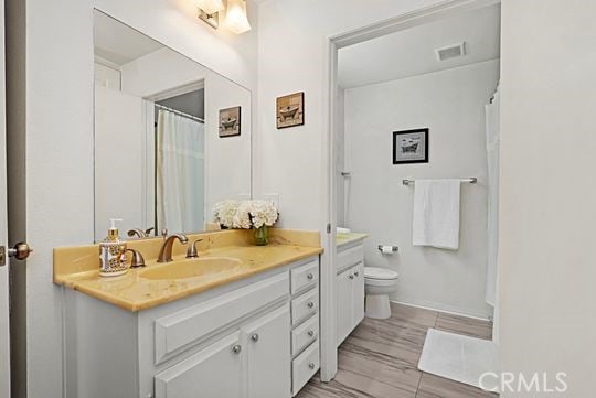 bathroom featuring vanity, wood-type flooring, and toilet