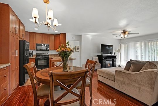 dining space with dark wood-type flooring and ceiling fan with notable chandelier