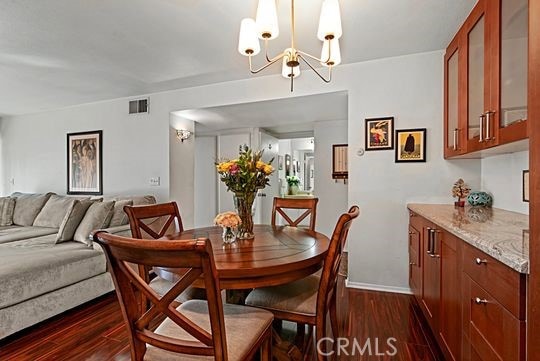 dining room with dark wood-type flooring and a notable chandelier