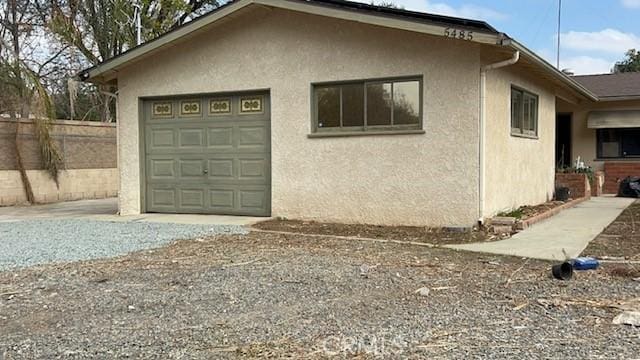 exterior space featuring a garage, fence, and stucco siding