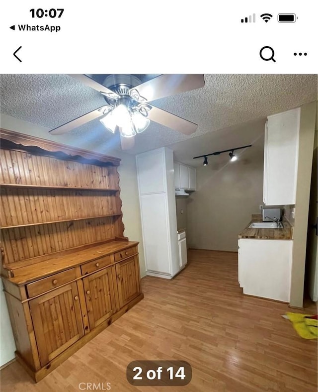 kitchen with white cabinetry, sink, ceiling fan, a textured ceiling, and light wood-type flooring