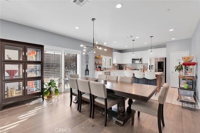 dining area featuring an inviting chandelier and light hardwood / wood-style floors