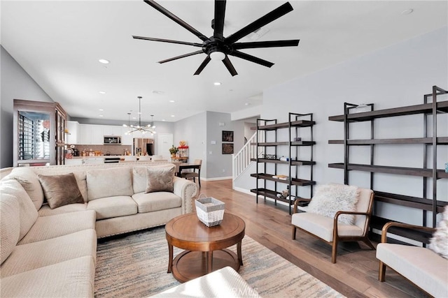 living room with ceiling fan with notable chandelier and light hardwood / wood-style floors