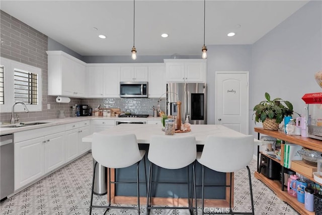 kitchen with pendant lighting, sink, a center island, light stone counters, and stainless steel appliances