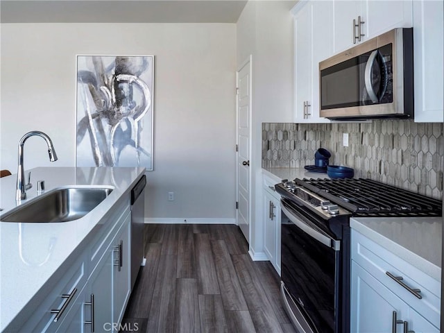 kitchen with sink, appliances with stainless steel finishes, white cabinetry, dark hardwood / wood-style flooring, and decorative backsplash