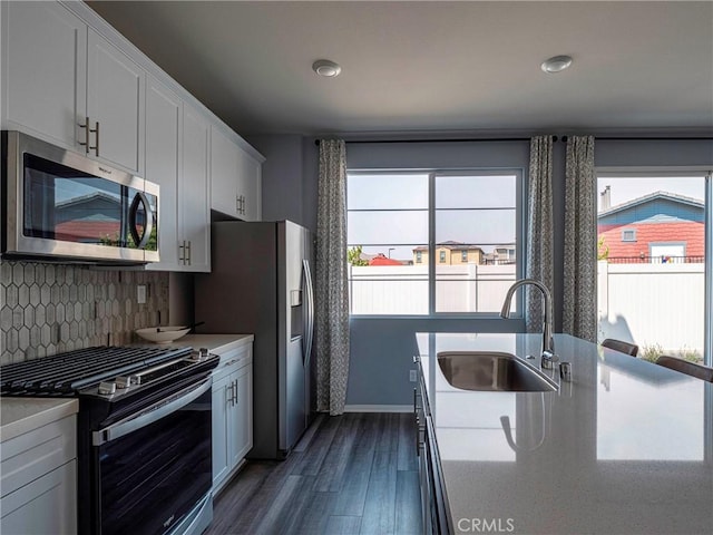 kitchen featuring white cabinetry, sink, backsplash, dark hardwood / wood-style flooring, and stainless steel appliances