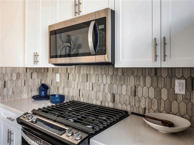 kitchen featuring backsplash, appliances with stainless steel finishes, and white cabinets