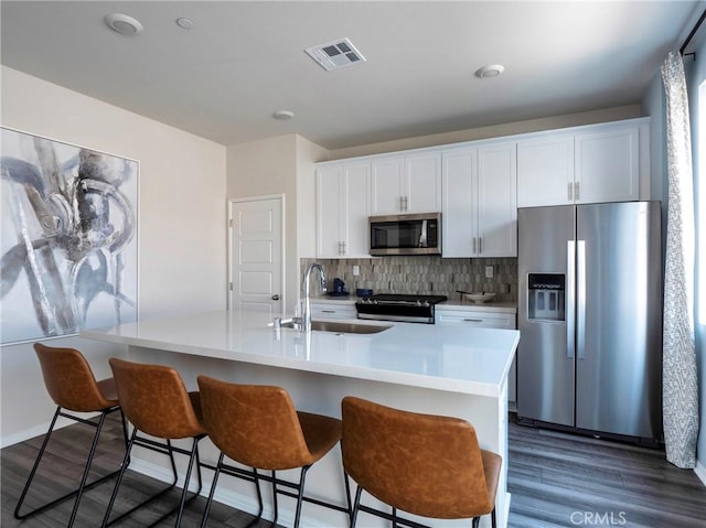 kitchen with white cabinetry, appliances with stainless steel finishes, sink, and a center island with sink