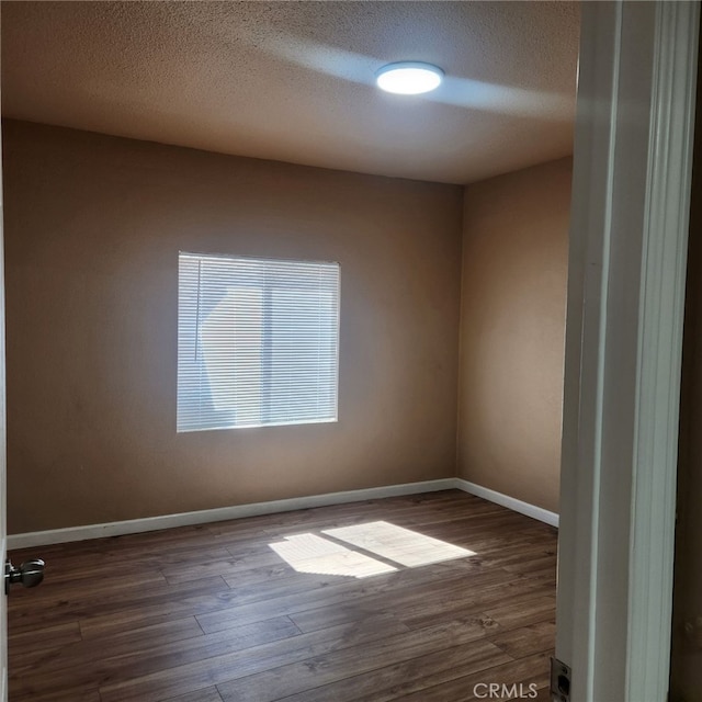 unfurnished room with dark wood-type flooring and a textured ceiling