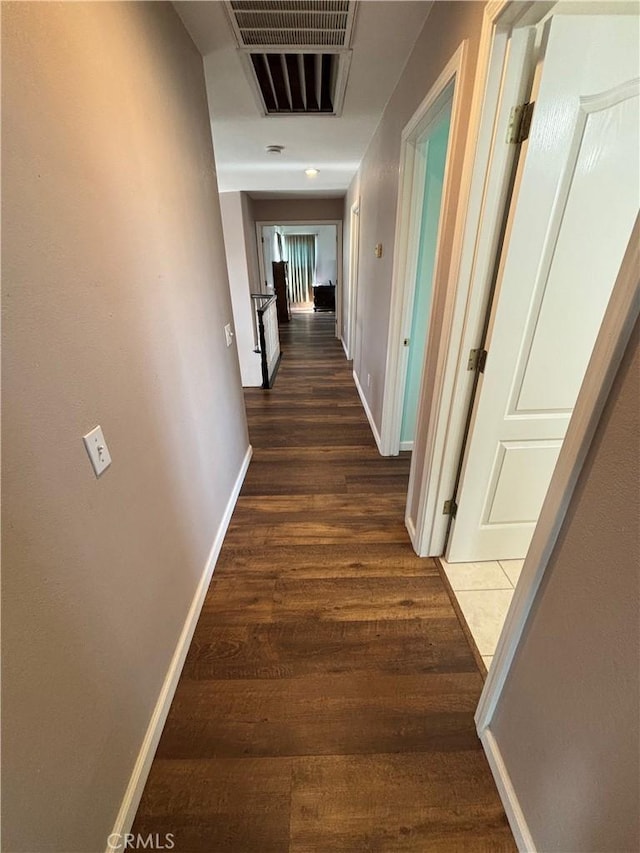 corridor featuring dark wood-style flooring, baseboards, and visible vents