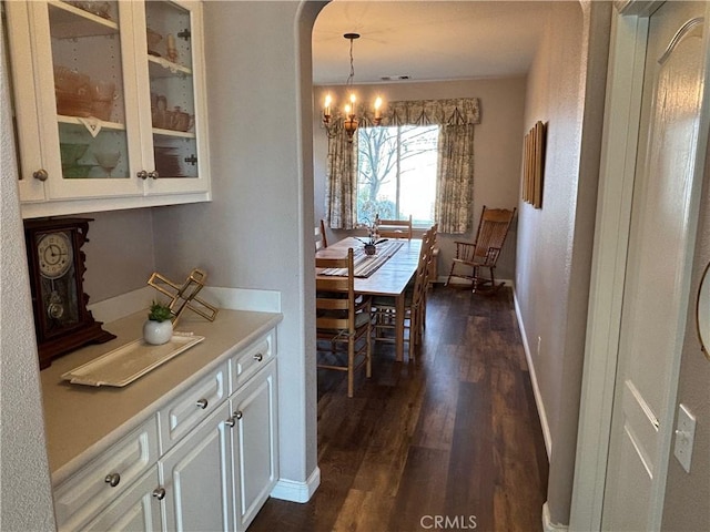 dining space featuring dark wood-type flooring, baseboards, and a chandelier