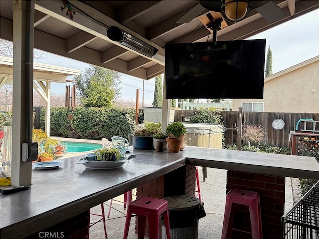 view of patio / terrace featuring a fenced backyard, outdoor dry bar, ceiling fan, and a hot tub