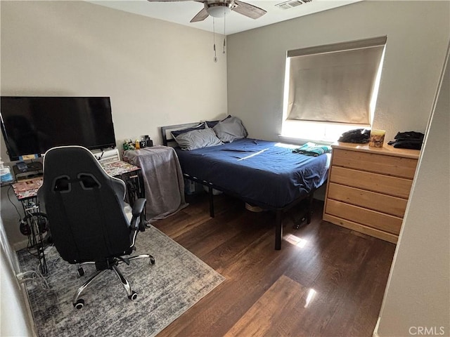 bedroom with dark wood-type flooring, ceiling fan, and visible vents