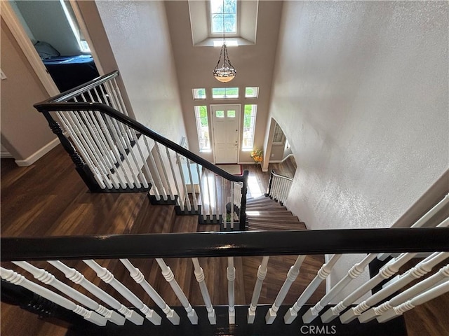 stairs featuring baseboards, a high ceiling, and wood finished floors