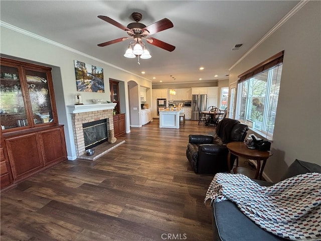 living room with ornamental molding, a ceiling fan, dark wood finished floors, and visible vents