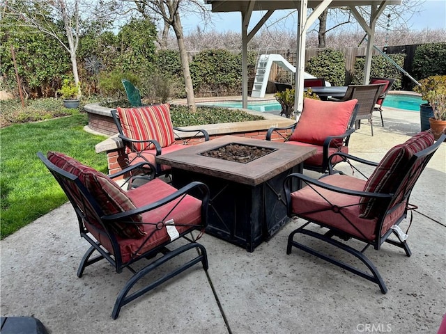 view of patio / terrace with fence private yard, a fire pit, and an outdoor pool
