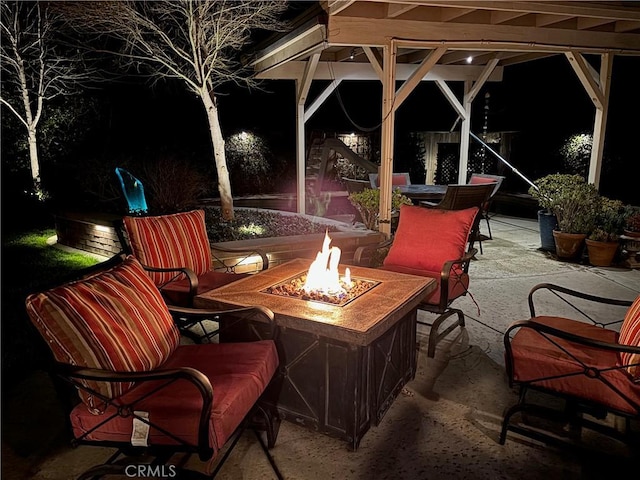 patio at night with outdoor dining space and an outdoor fire pit