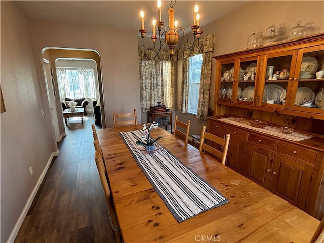 dining area with an inviting chandelier, baseboards, arched walkways, and wood finished floors