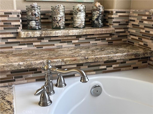 details with a textured wall, decorative backsplash, and a sink