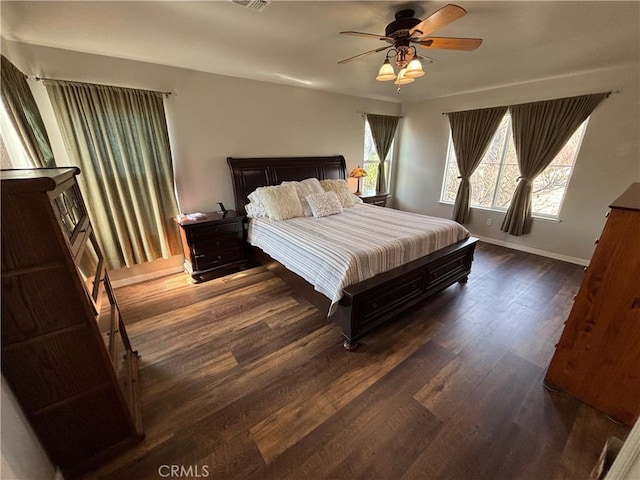 bedroom featuring a ceiling fan, baseboards, dark wood finished floors, and visible vents