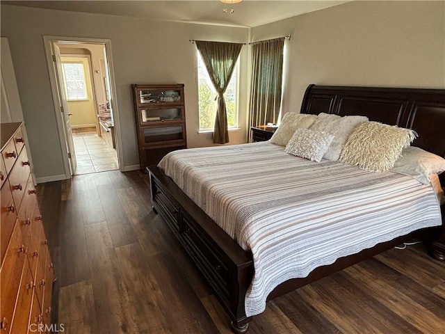 bedroom featuring baseboards, wood finished floors, and multiple windows