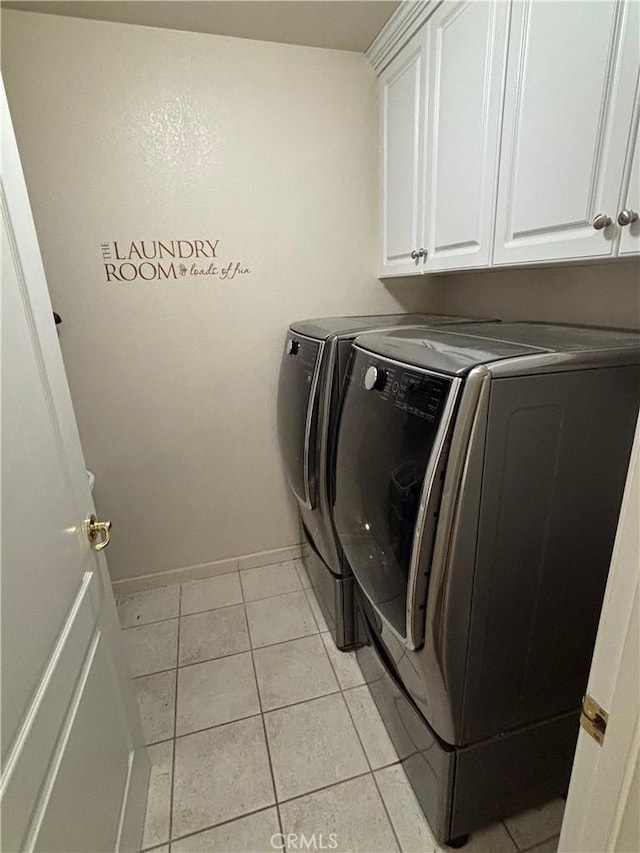 washroom featuring baseboards, cabinet space, light tile patterned floors, and washer and dryer